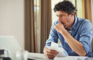 stressed man looks at household bills
